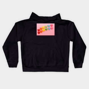 Heart-shaped Candy arranged in rainbow order on a pink background Kids Hoodie